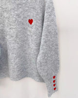 Pull gris coeurs rouges sur poignets 