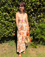 robe longue d'été imprimée tropicale, dos croisé et bretelles fines, coupe fluide bohème dans un jardin ensoleillé